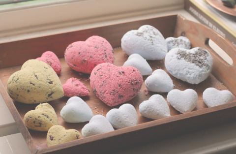 Heart shaped bath bombs sitting in a wooden tray.